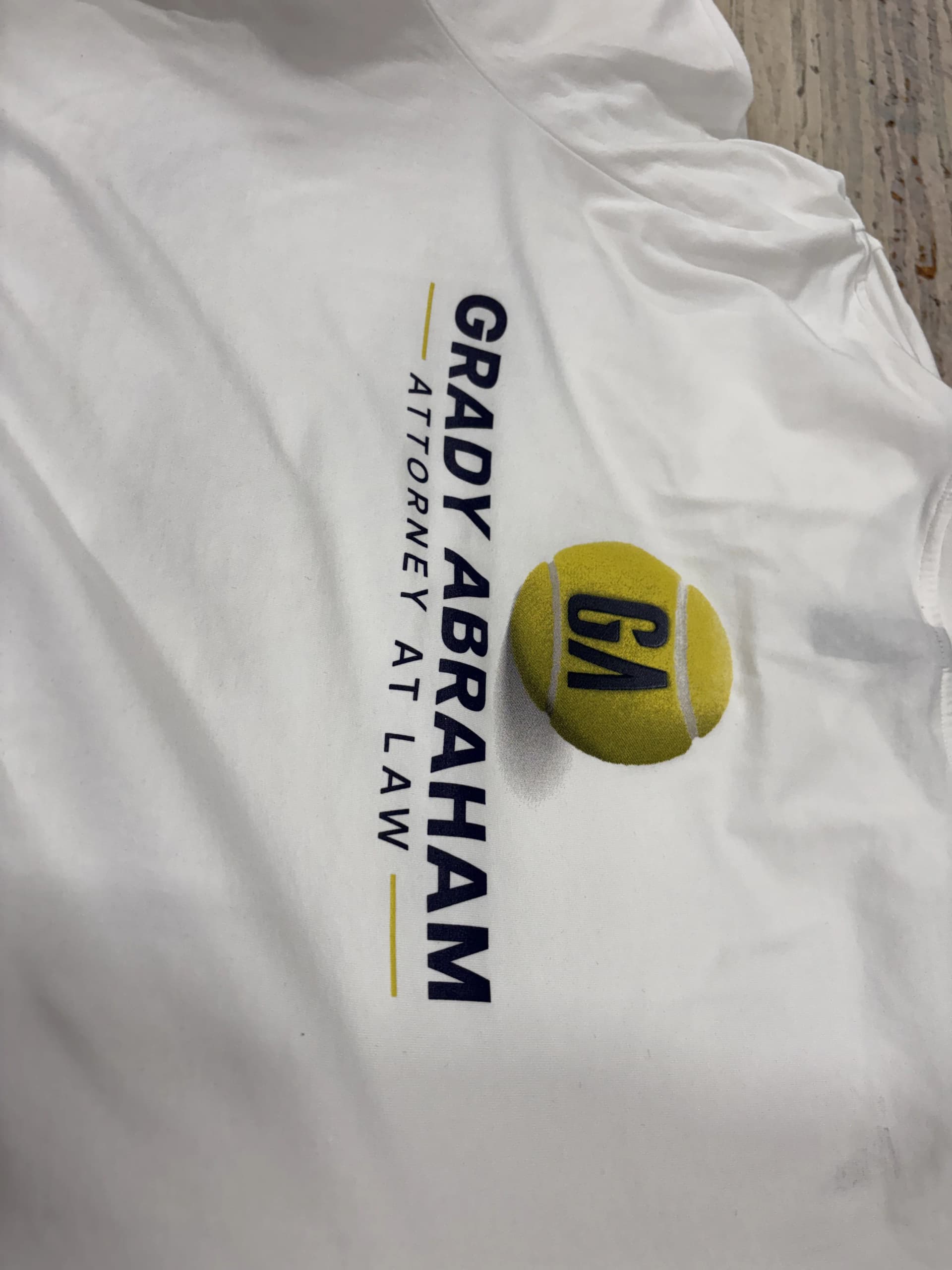 White short-sleeve polo shirt with embroidered text GRADY ABRAHAM ATTORNEY AT LAW and a GA logo on the left chest