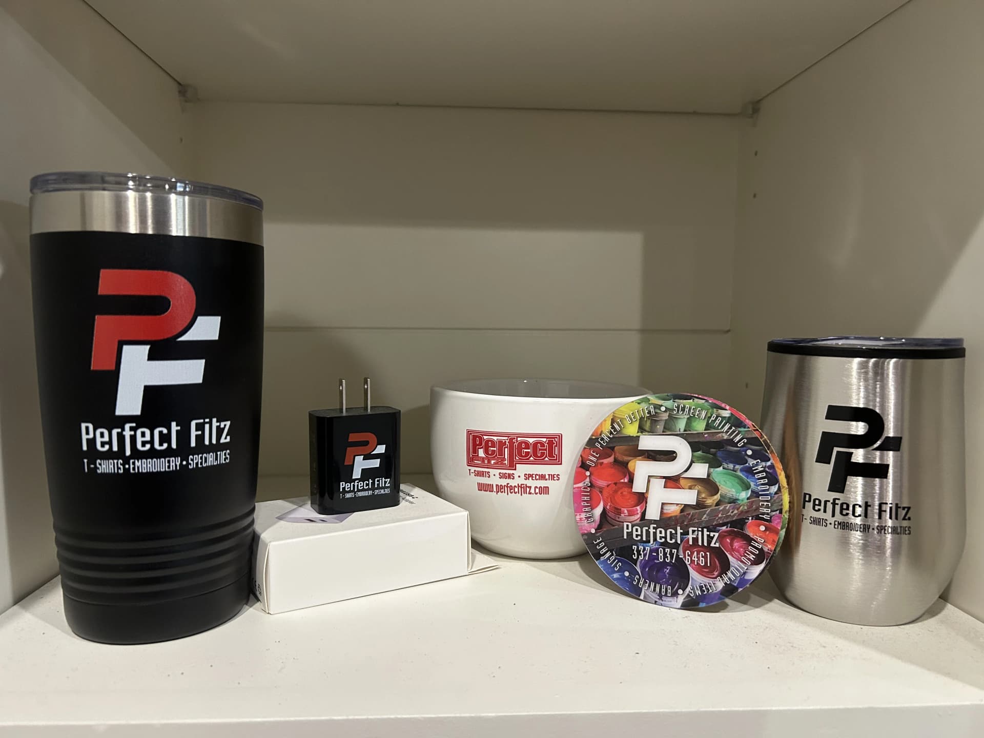Collection of white and stainless steel tumblers branded with the Perfect Fitz logo and services